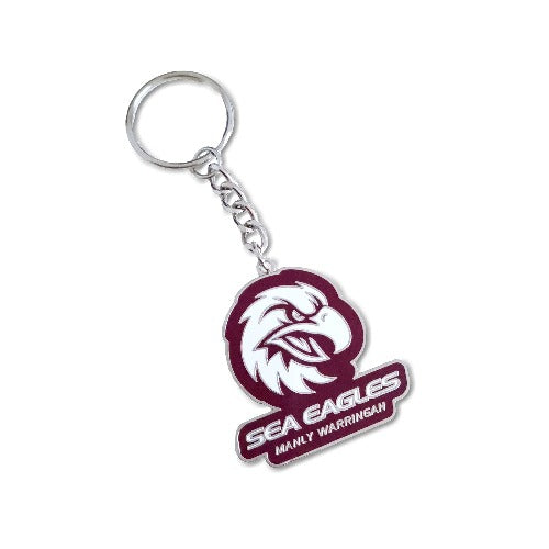 A metal keyring with a Manly Sea Eagles logo, predominantly maroon and white in color, attached to a keychain.